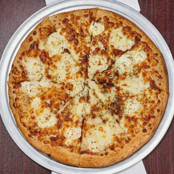 A whole white pizza with melted cheese and herbs, sliced into eight pieces on a metal tray.