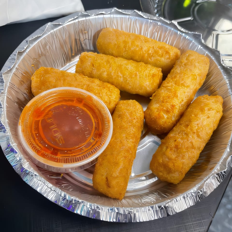 Seven golden-brown fried mozzarella sticks and a small cup of red dipping sauce in a foil container.
